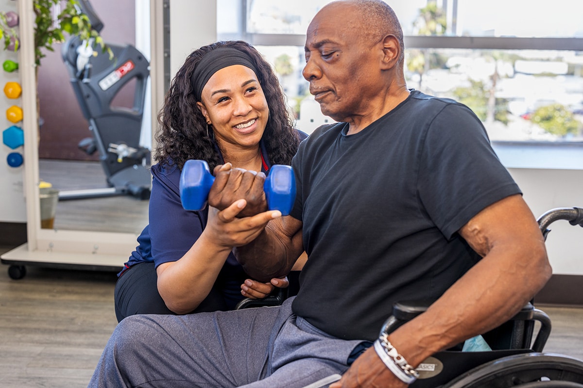 A female rehab therapist with a resident in the rehab gym at Beachwood Post-Acute and Rehab